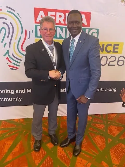 Two men shaking hands in front of the Africa Running Conference 2026 backdrop.