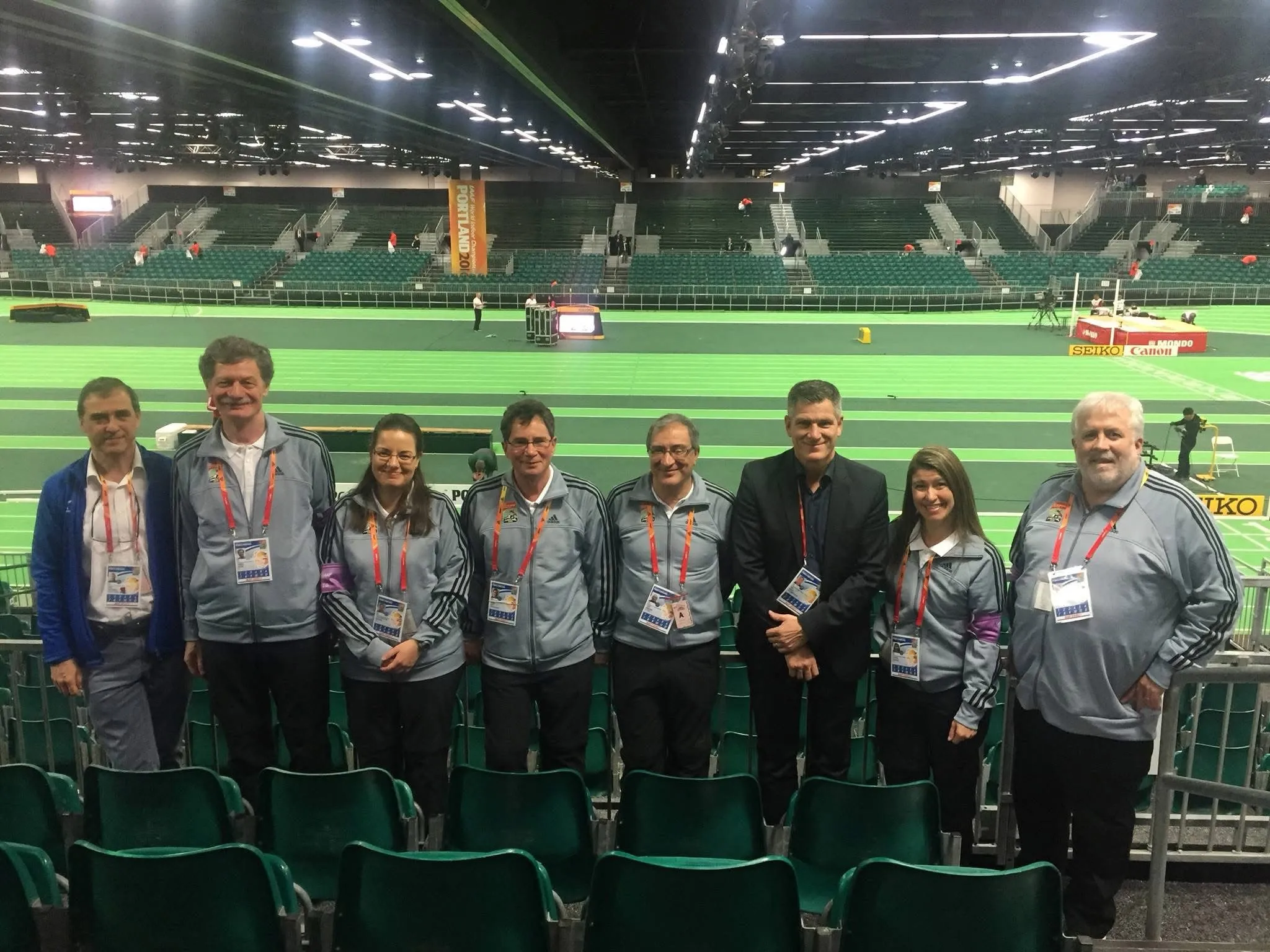 A technical team standing in front of an indoor stadium track.