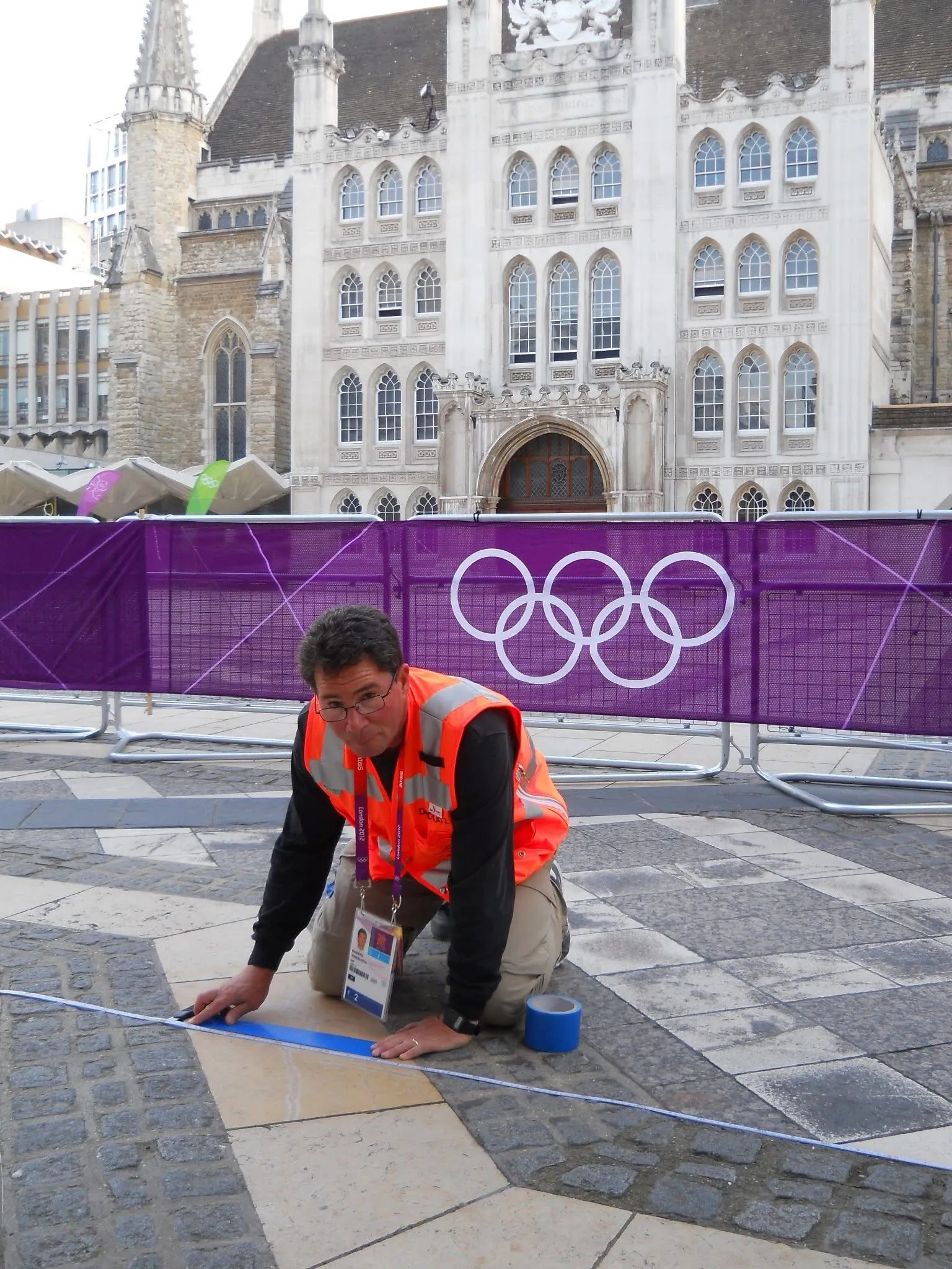 A measurer in a high-visibility vest taping a mark on the London 2012 Olympic road course.