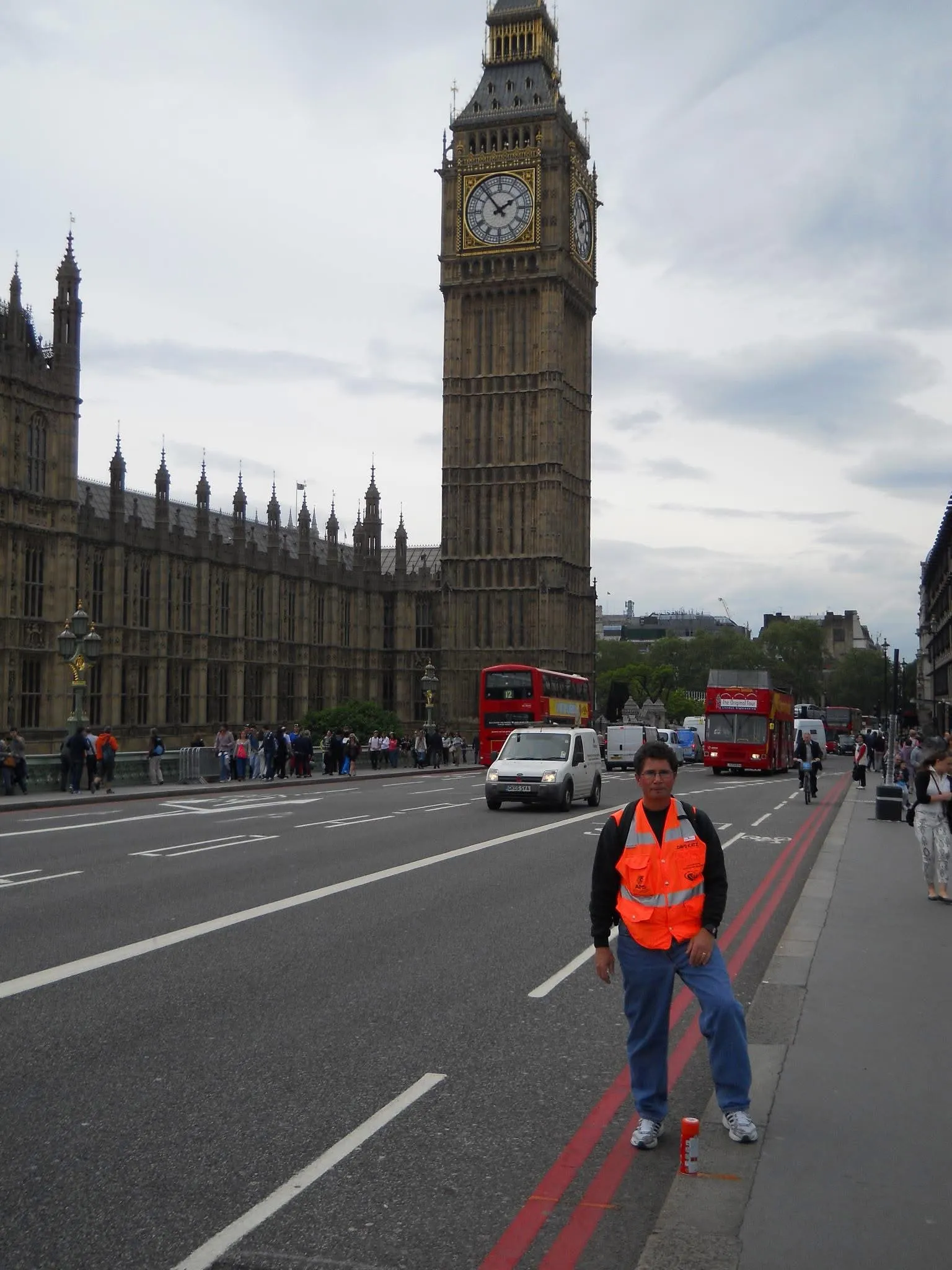 A measurer in an orange vest on a London street, Big Ben behind.