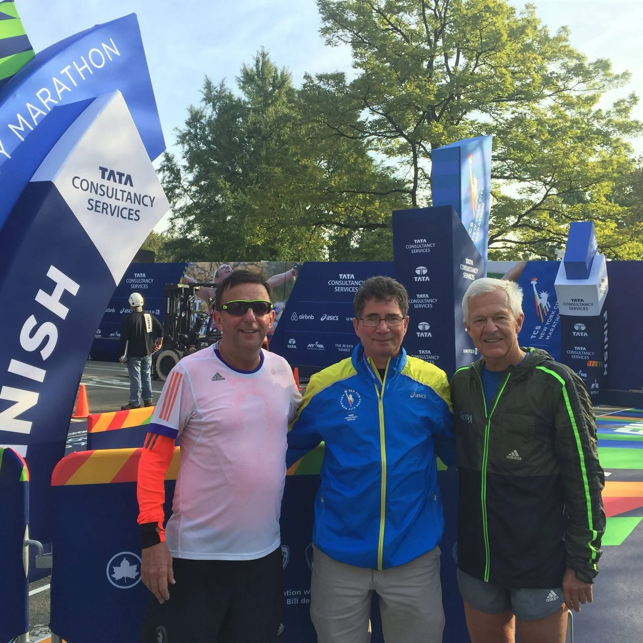Three men posing at the New York City Marathon finish line.